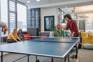 Business colleagues take a break from work to enjoy a game of table tennis, fostering teamwork and camaraderie in the workplace photo