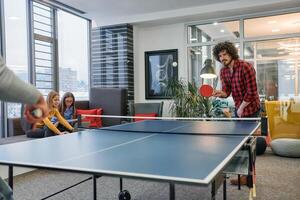 Business colleagues take a break from work to enjoy a game of table tennis, fostering teamwork and camaraderie in the workplace photo