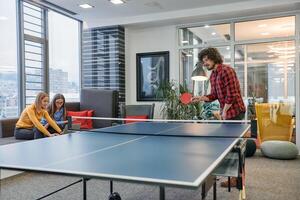 Business colleagues take a break from work to enjoy a game of table tennis, fostering teamwork and camaraderie in the workplace photo