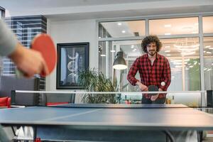 Business colleagues take a break from work to enjoy a game of table tennis, fostering teamwork and camaraderie in the workplace photo