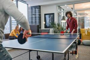 Business colleagues take a break from work to enjoy a game of table tennis, fostering teamwork and camaraderie in the workplace photo