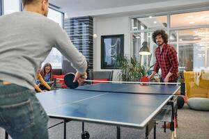 Business colleagues take a break from work to enjoy a game of table tennis, fostering teamwork and camaraderie in the workplace photo