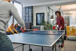 Business colleagues take a break from work to enjoy a game of table tennis, fostering teamwork and camaraderie in the workplace photo