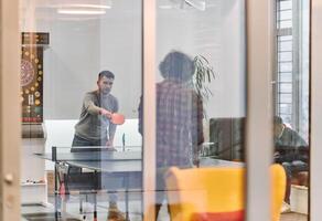 Business colleagues take a break from work to enjoy a game of table tennis, fostering teamwork and camaraderie in the workplace photo