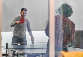 Business colleagues take a break from work to enjoy a game of table tennis, fostering teamwork and camaraderie in the workplace photo