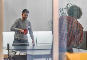Business colleagues take a break from work to enjoy a game of table tennis, fostering teamwork and camaraderie in the workplace photo
