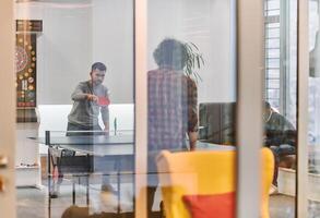 Business colleagues take a break from work to enjoy a game of table tennis, fostering teamwork and camaraderie in the workplace photo