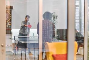 Business colleagues take a break from work to enjoy a game of table tennis, fostering teamwork and camaraderie in the workplace photo