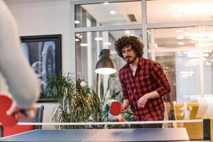Business colleagues take a break from work to enjoy a game of table tennis, fostering teamwork and camaraderie in the workplace photo