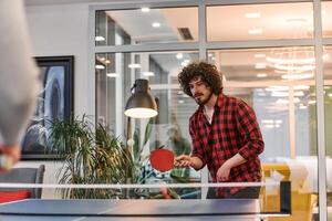 Business colleagues take a break from work to enjoy a game of table tennis, fostering teamwork and camaraderie in the workplace photo