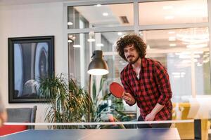 Business colleagues take a break from work to enjoy a game of table tennis, fostering teamwork and camaraderie in the workplace photo