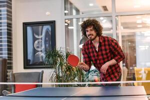 Business colleagues take a break from work to enjoy a game of table tennis, fostering teamwork and camaraderie in the workplace photo