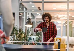 Business colleagues take a break from work to enjoy a game of table tennis, fostering teamwork and camaraderie in the workplace photo