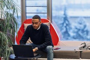 Overtime working. African American man with closed eyes is resting at work at laptop. Tired male programmer taking a break due to overtime work. photo