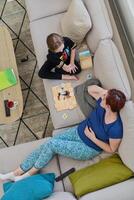 Top View of Mother and Daughter Enjoying a Fun Board Game on the Couch at Home photo