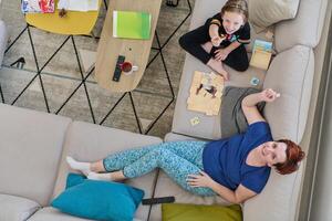 Top View of Mother and Daughter Enjoying a Fun Board Game on the Couch at Home photo