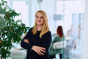 Brunette Businesswoman with Crossed Arms Standing in Front of Modern Office. photo