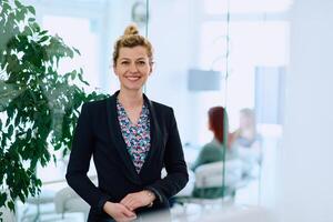 Portrait of a Blonde Businesswoman in a Modern Office with Her Workspace and Colleagues in the Background. photo