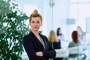 Brunette Businesswoman with Crossed Arms Standing in Front of Modern Office. photo