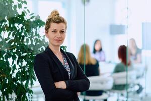 Brunette Businesswoman with Crossed Arms Standing in Front of Modern Office. photo