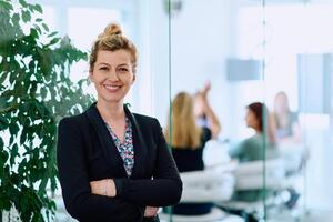Brunette Businesswoman with Crossed Arms Standing in Front of Modern Office. photo