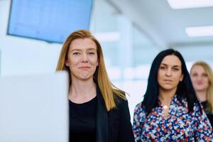 Confident businesswomen stride through the office hallway, deep in discussion. photo