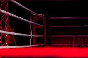 Empty boxing ring with red ropes for match in the stadium arena. Creative artwork decoration. Foggy background with light. Selective focus photo