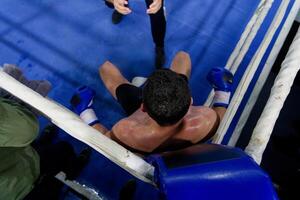 Top view of cornered boxer receives strategic advice from trainer during intense bout. photo