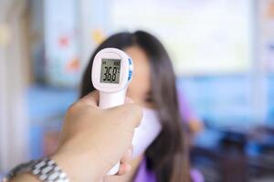 Operator Check Fever by Digital Thermometer Visitor at Information Counter for Scan and Protect from Coronavirus COVID-19 Outbreak - Healthcare Concept photo