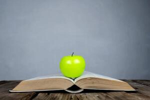 Books placed on the table and on top are green apple. photo