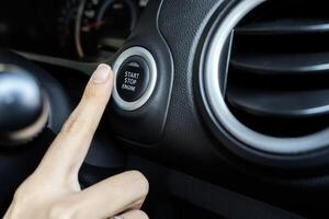 Using the push button to start and stop engine, The woman's finger is pressing down. photo