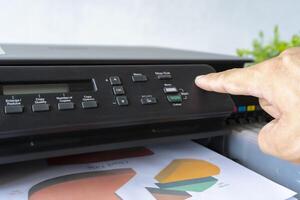 Fingers that are pressing the button, The printer is fully functional,Located on the desk. photo