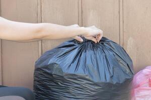 woman putting garbage bag into trash can. Bind it to make it easy to move. photo