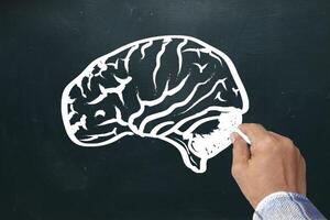 Hand drawing brain sketch on blackboard. Brainstorming and idea concept photo