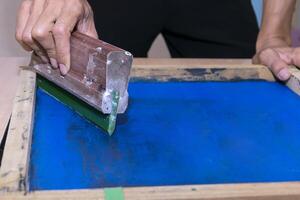 Young confident, experienced male working with squeegee on a small factory. photo