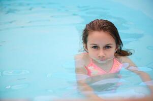 Young girl in a colorful swimsuit swimming in a pool photo