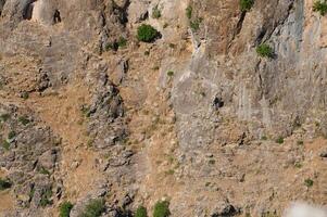 Natural rock formation with small patches of greenery in a rugged mountainous area photo