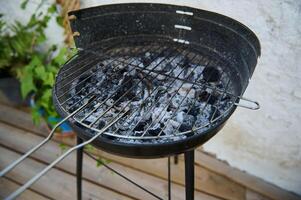 Empty charcoal grill with ashes and charred remains after a barbecue in a backyard setting photo