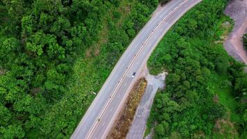 Aerial view of countryside asphalt road with car and green forest. Drive on the road between green forests. video