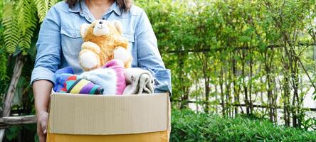 Volunteer collect cloth and doll in cardboard box to donate. photo