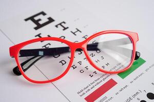 Glasses on eye exam chart to test eyesight accuracy of reading. photo