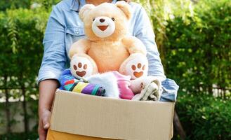 Volunteer collect cloth and doll in cardboard box to donate. photo