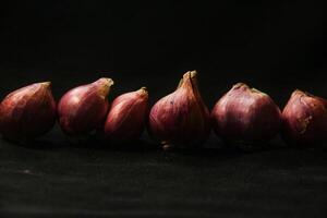 Close up of a whole red onion, isolated on a black background photo