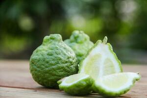 Bergamot fruits or sliced kaffir lime on wooden table and natural green background photo