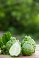 Bergamot fruits or sliced kaffir lime on wooden table and natural green background photo