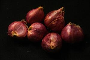 Close up of a whole red onion, isolated on a black background photo