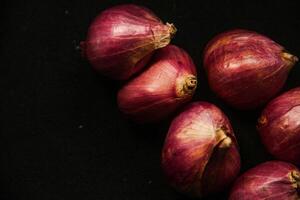 Close up of a whole red onion, isolated on a black background photo