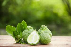 Bergamot fruits or sliced kaffir lime on wooden table and natural green background photo