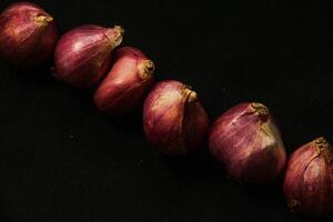 Close up of a whole red onion, isolated on a black background photo