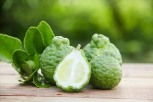 Bergamot fruits or sliced kaffir lime on wooden table and natural green background photo